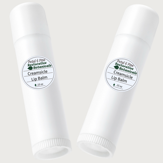 Two white lip balm tubes with Petal & Pine Creamsicle labels on a light gray background