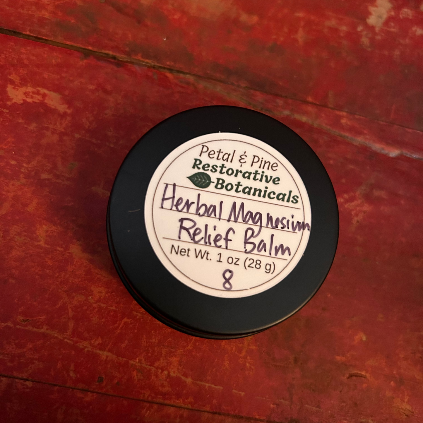 Herbal Magnesium Relief Balm 1 oz Black Container with White Label and Petal & Pine Restorative Botanicals Logo