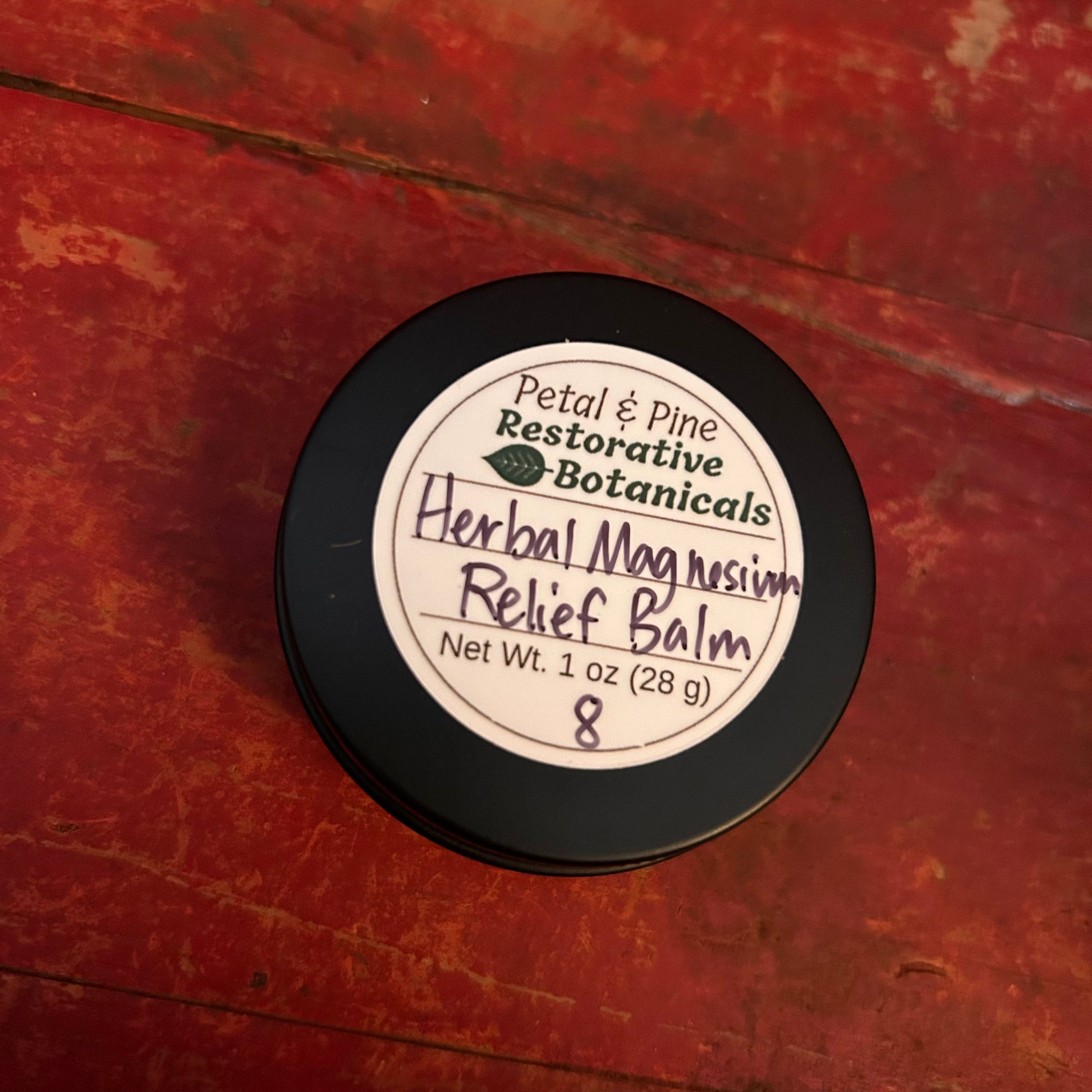 Herbal Magnesium Relief Balm 1 oz Black Container with White Label and Petal & Pine Restorative Botanicals Logo