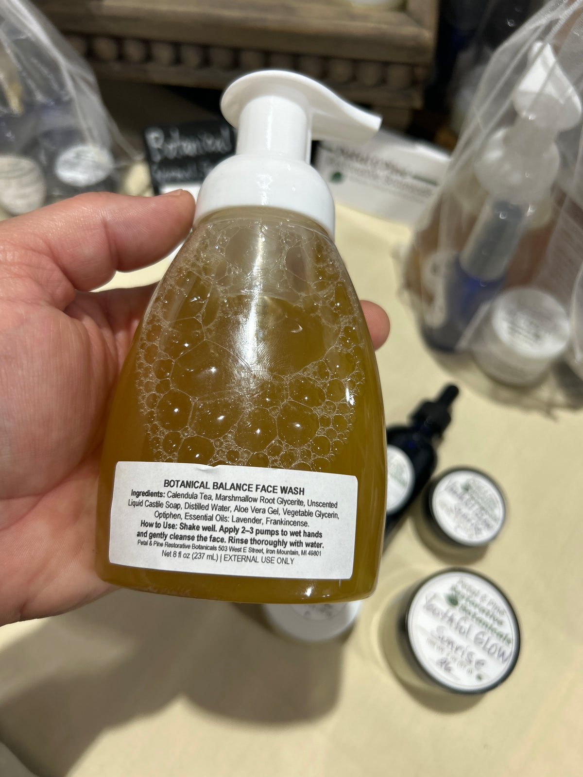 Hand holding Botanical Balance Face Wash showing the ingredient label
